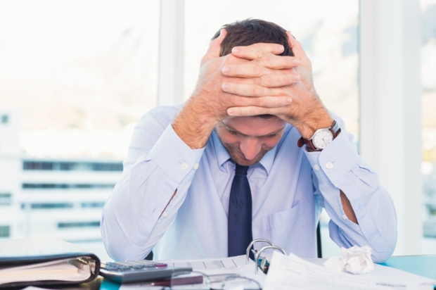 Stressed-businessman-with-head-in-hands
